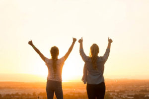 girls facing a sunset
